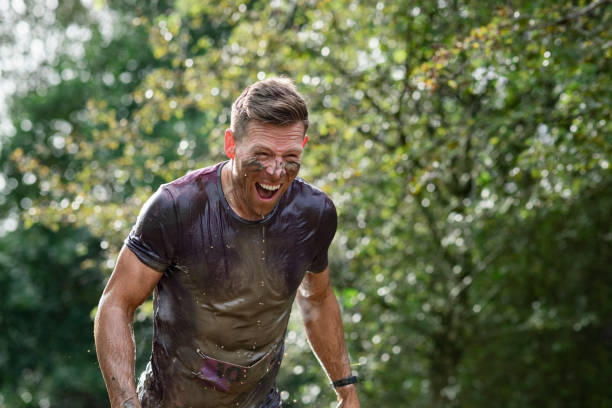 homme boueux ruisselant sur la course de cross-country - mud run photos et images de collection