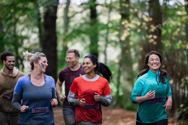 Adult friends running outdoors in country park Cheerful friends running together in countryside, training, healthy, happy stampeding photos stock pictures, royalty-free photos & images