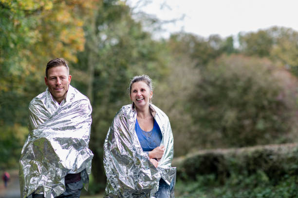 Muddy couple in foil blankets leaving event together Charity runners leaving Stampede event and keeping warm, achievement, fundraising, success stampeding photos stock pictures, royalty-free photos & images