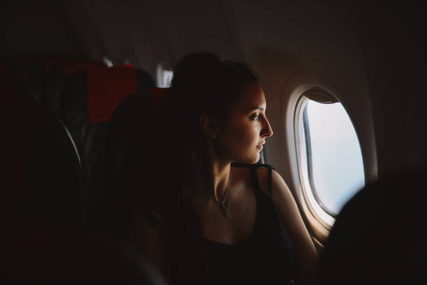 istock Woman in the plane looking through the window 1204008418