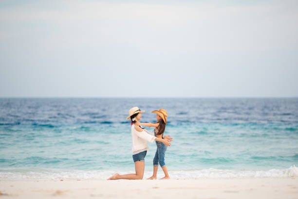 istock Mother and daughter playing on the beach 1204009137