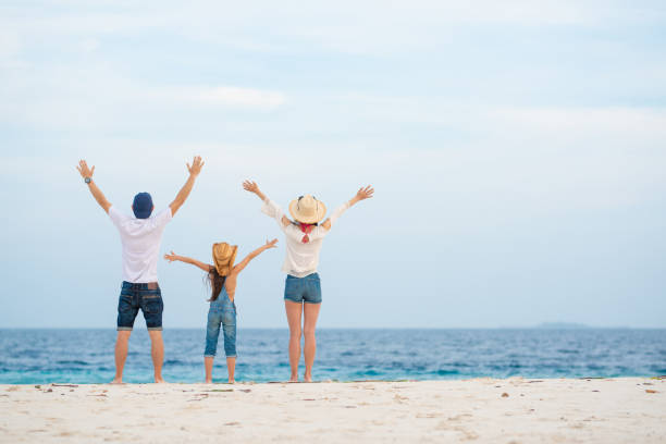 istock Father and mother and daughter to spread both hands on the beach 1204009243