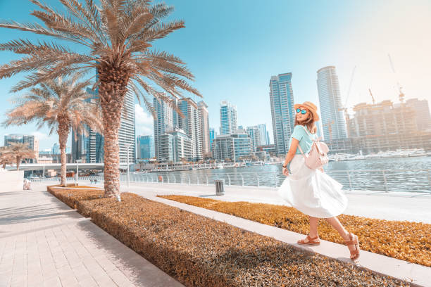 glücklich asiatische mädchen zu fuß auf einer promenade in dubai marina bezirk. reisen und lifestyle in vereinigte arabische emirate - united arab emirates dubai marina asia arabia stock-fotos und bilder