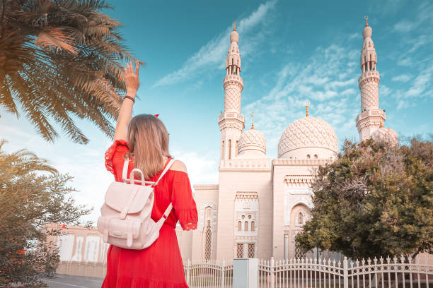 garota turista acenando de mãos perto da mesquita de jumeirah em dubai, emirados americanos. conceito de viagem e religião - jumeirah mosque - fotografias e filmes do acervo