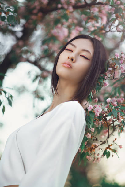 istock Asian woman outdoors on spring against flower blossom 1204009572