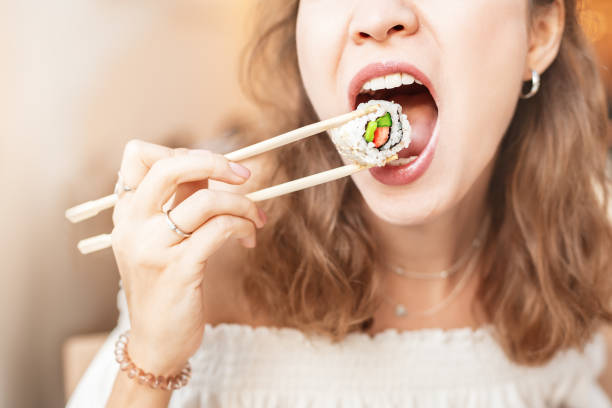 menina comendo sushi com pauzinhos enquanto almoçabento na praça de alimentação - black dishware sushi isolated - fotografias e filmes do acervo