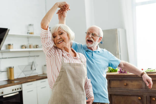 selektiver fokus des lächelnden senior-paares tanzen in der küche - senior couple stock-fotos und bilder