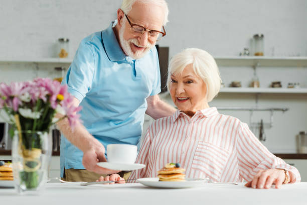 istock Selective focus of senior man putting coffee on table by smiling wife during breakfast 1204011348