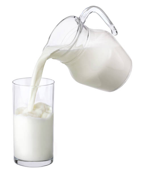 istock Pouring milk from jug into glass isolated on white background 1204013964