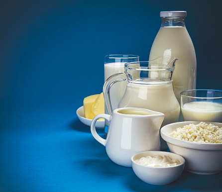 Set of dairy products on blue wooden background, assortment of milk, cottage cheese, sour cream and yogurt with copy space