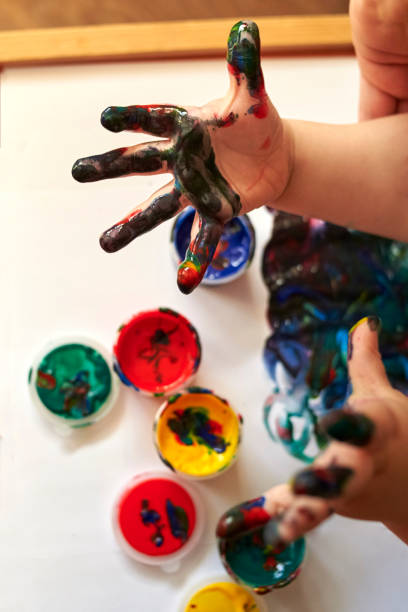 istock Hands of a child who paints with bright finger paints 1204015079