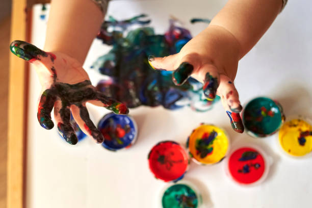 istock Hands of a child who paints with bright finger paints 1204015088