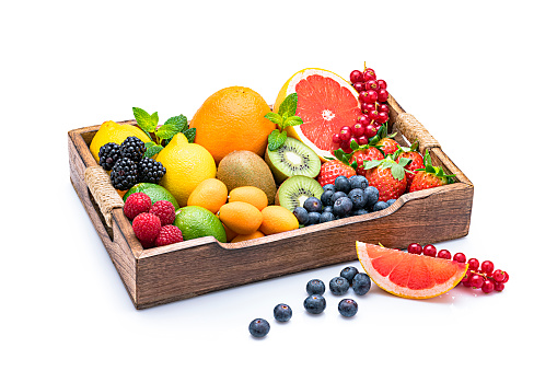 Wooden tray filled with a variety of multicolored healthy fruits isolated on white background. Fruits included in the composition are grapefruit, kiwi fruit, strawberries, various berries, lemons, lime and mint twigs. High resolution 42Mp studio digital capture taken with Sony A7rii and Sony FE 90mm f2.8 macro G OSS lens