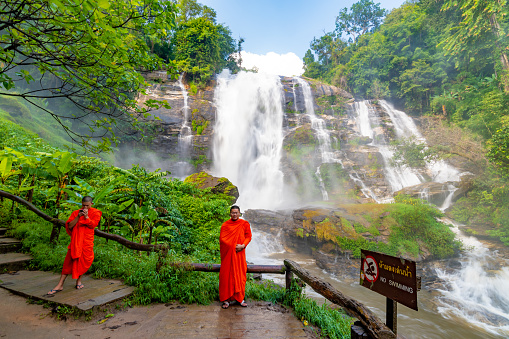 CHIANG MAI, THAILAND - 5.11.2019: Buddhist monk is taking photo near Wachirathan waterfall in tropical jungle and rainforest.