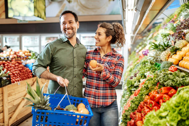 couples latinos achetant la nourriture végétalienne - supermarket groceries shopping healthy lifestyle photos et images de collection