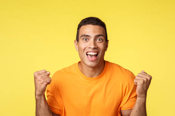 istock Achievement, celebration and win concept. Handsome relieved cheerful young man clench hands, fist pump and smiling become winner or champion, receive prize, achieve success, yellow background 1204019394