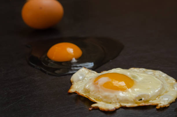 istock Close-up of a line of whole chicken eggs, raw broken and fried egg. 1204019571