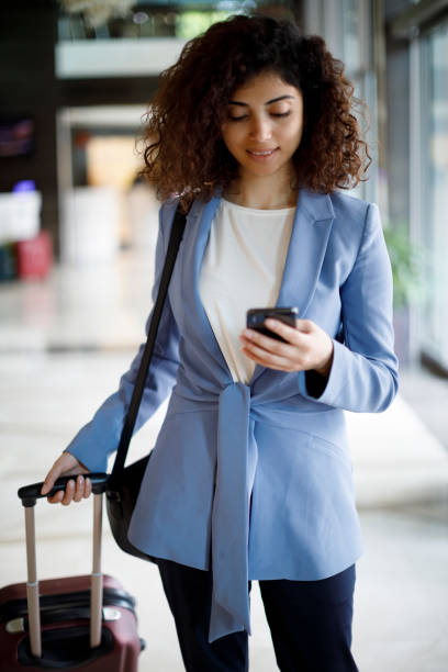 istock Businesswoman with suitcase using mobile phone 1204024246