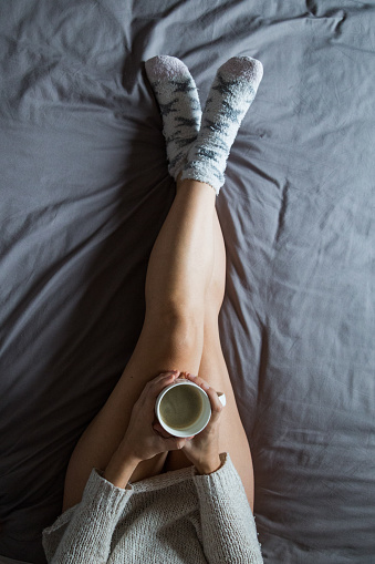 young woman having coffee on bed at morning