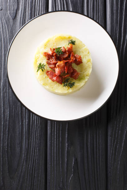 istock Andorian cuisine Trinxat spicy mashed cabbage potato topped with fried bacon closeup in a plate. Vertical top view 1204026838