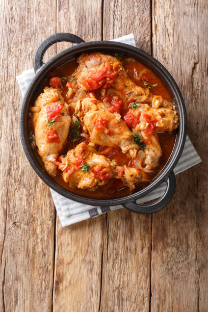 istock Braised rabbit in tomato sauce with white wine and herbs close-up in a pan. Vertical top view 1204026876