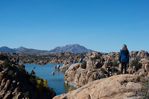School-age girl on a hike pausing to look out over Watson Lake in the Granite Dells in Prescott, Arizona.