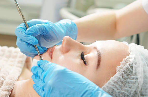 istock Cosmetologist doing mechanical face peeling treatment for the patient face, close up 1204030668