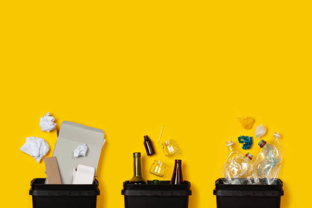 Separate collection of waste Paper, glass, plastic in black containers on a yellow background. The concept of separate collection of waste, sorting of waste, recycle, informed consumption. Flat lay. Copy space. plastic pollution photos stock pictures, royalty-free photos & images