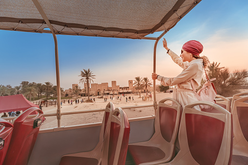 A happy girl in an Indian headdress travels on the roof of a bus in a natural and historical Park. Desert Safari and adventure concept