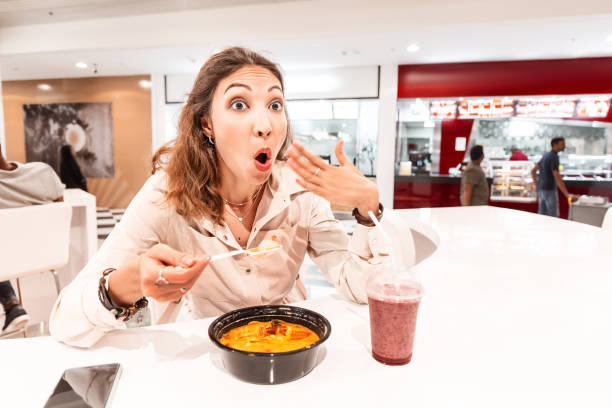 uma mulher comendo sopa muito quente e apimentada em um restaurante asiático de fast food. conceito de especiarias na culinária oriental - oriental - fotografias e filmes do acervo