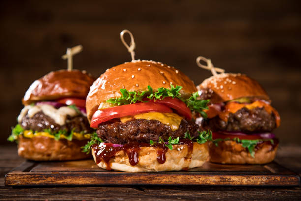 istock Tasty burgers on wooden table. 1204033248