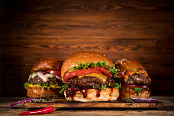 istock Tasty burgers on wooden table. 1204033295