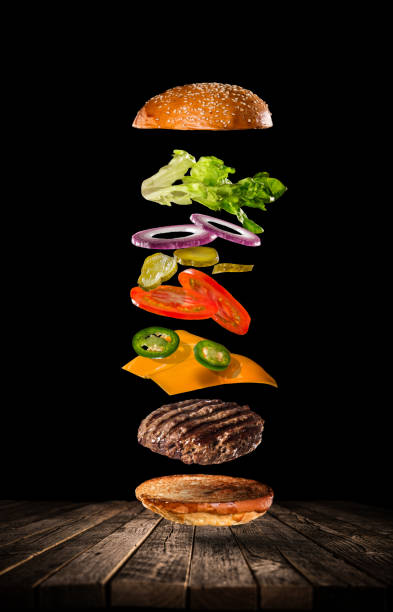 istock Tasty hamburger with flying ingredients on dark background 1204033404