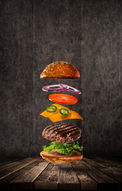 istock Tasty hamburger with flying ingredients on dark background 1204033424