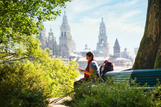 Tourist Woman On Pilgrimage At Santiago De Compostela With Phone Female Pilgrim Typing Message On Mobile Telephone In Santiago De Compostela, The End Of The Way of St James, With Cathedral In Background. camino de santiago photos stock pictures, royalty-free photos & images