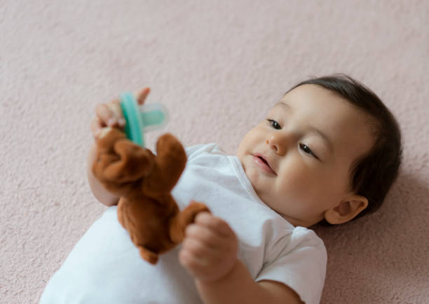 istock Cute baby boy lying on carpet playing with a toy 1204037984