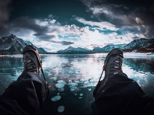 man lying down on the frozen lake, abraham lake, alberta, canada.