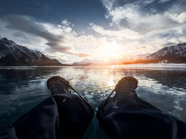 man lying down on the frozen lake, abraham lake, alberta, canada.