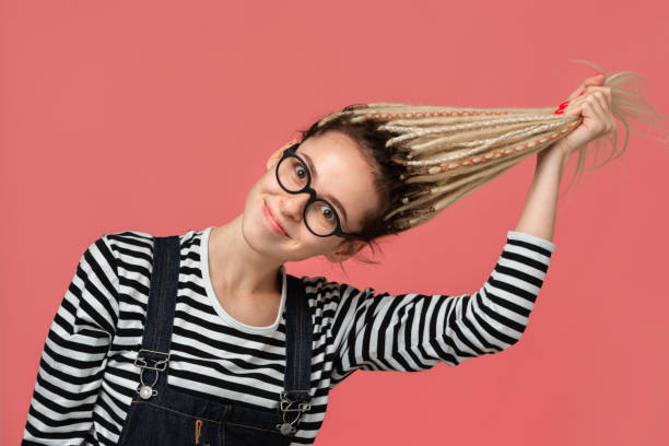 istock Young girl stretching her long blond dreads standing over pink background 1204043610