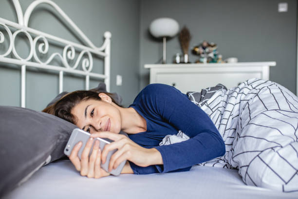 istock Young woman in bed using smart phone 1204044498