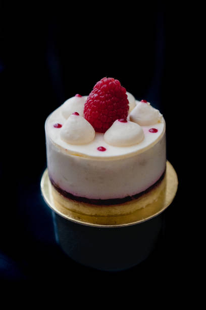 Luxury white cheesecake mousse cake decorated with fresh raspberries on a dark background. Flat lay. Close-up. Copy space