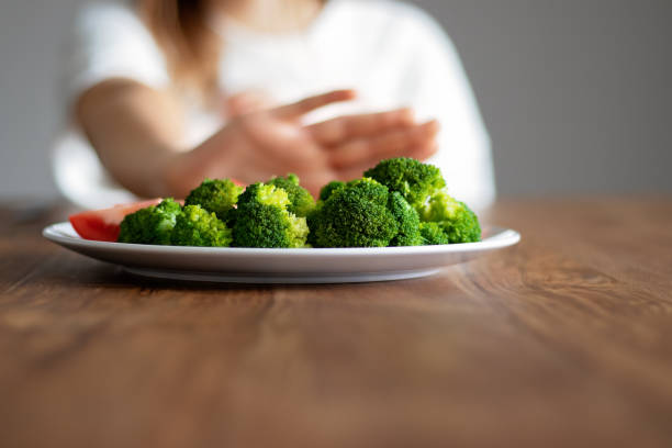 No vegan diet concept. Teen girl pushing away plate with broccoli and other vegetables refusing to eat. Food waste. Copy space. Selective focus on food. No vegan diet concept. Teen girl pushing away plate with broccoli and other vegetables refusing to eat. Food waste. Copy space. Selective focus on food. anorexia nervosa stock pictures, royalty-free photos & images