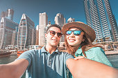 A couple in love takes a selfie in a seaport with a view of huge skyscrapers. Romantic honeymoon trips to Dubai Marina