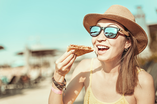 Happy girl eating Mexican fast food quesadilla on the beach. Healthy and tasty snack