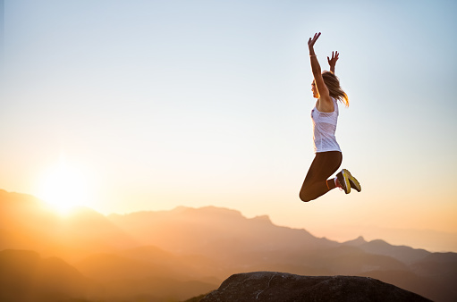 Shot of a woman jumping into the air enthusiastically while at the mountain