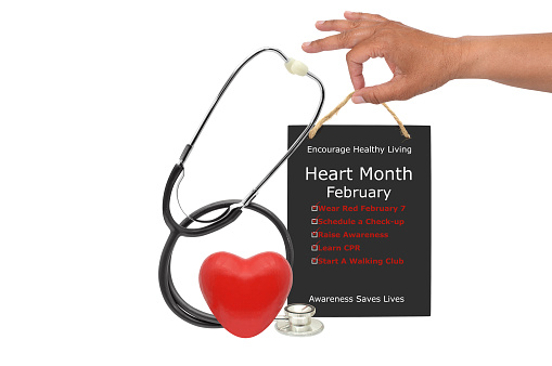 Red heart and stethoscope  in front of hand holding blackboard sign (Wear Red February 7, Schedule a Checkup, Raise Awareness, Learn CPR, Start A Walking club)  white background