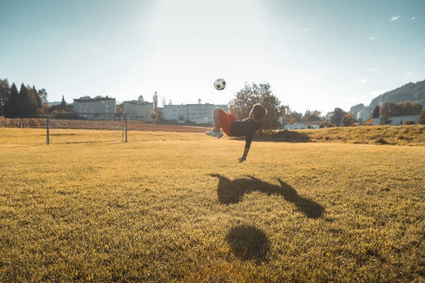 istock teen boy doing a bicycle kick in the evening sunlight 1204061920