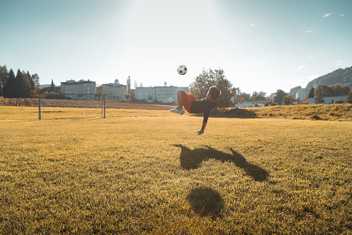 teen boy doing a bicycle kick in the evening sunlight