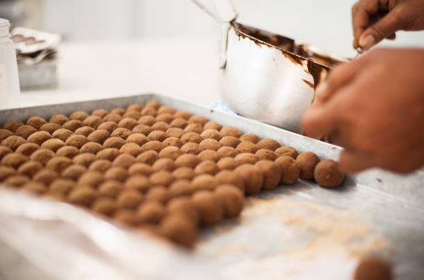 Chocolate production Close-up shot of a professional confectioner preparing chocolate balls at confectionery shop chocolate truffle making stock pictures, royalty-free photos & images