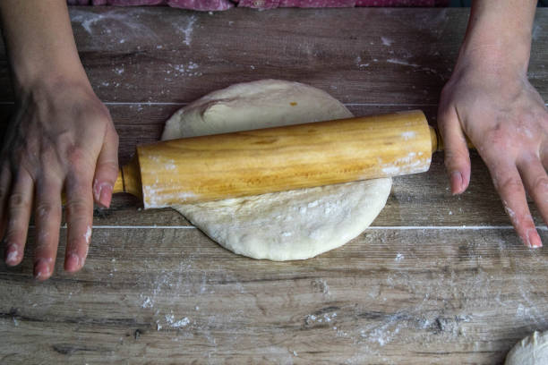 istock Women's hands mix the dough on a wooden table. Preparing bread for baking 1204066193